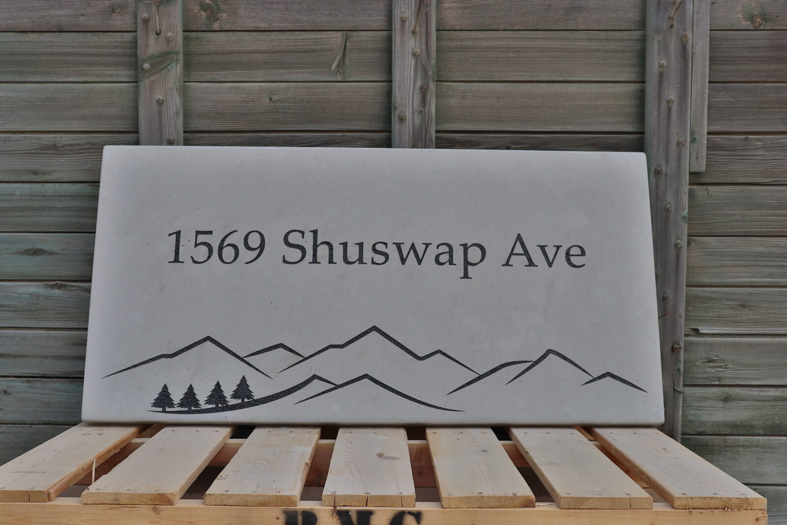 Engraved concrete address stone in natural grey with a mountain range and pine trees below the address