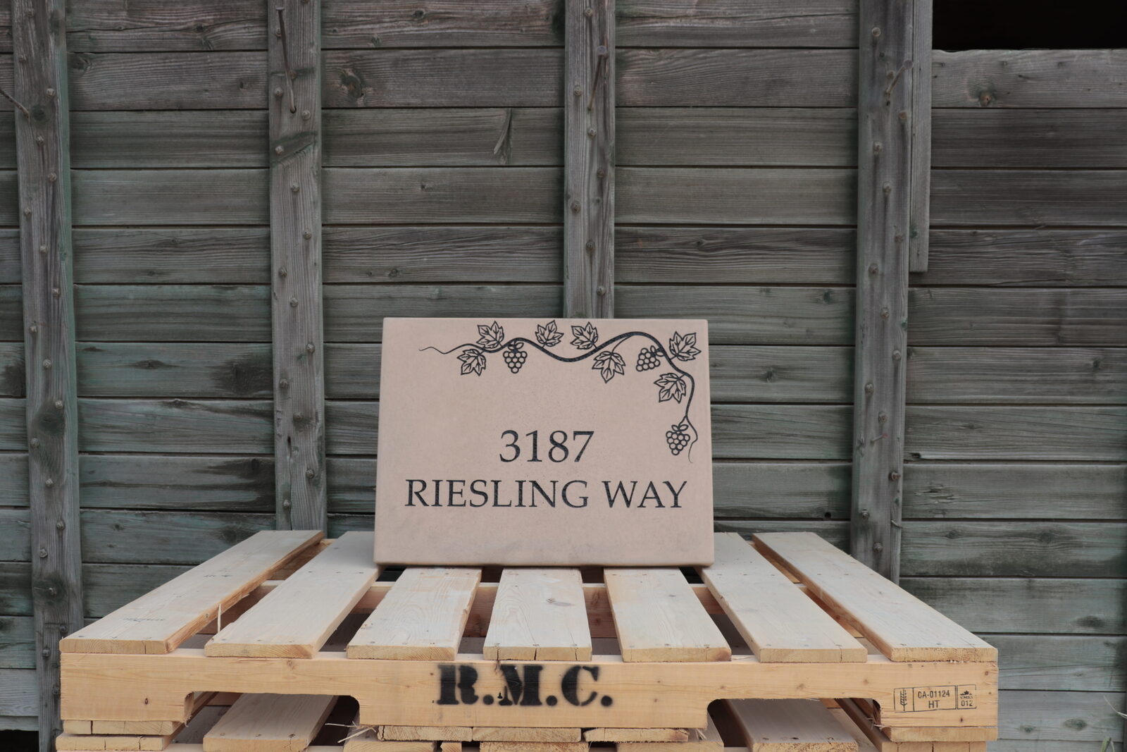 Engraved concrete address plaque in desert sand with a grapevine and grape clusters trailing the corner